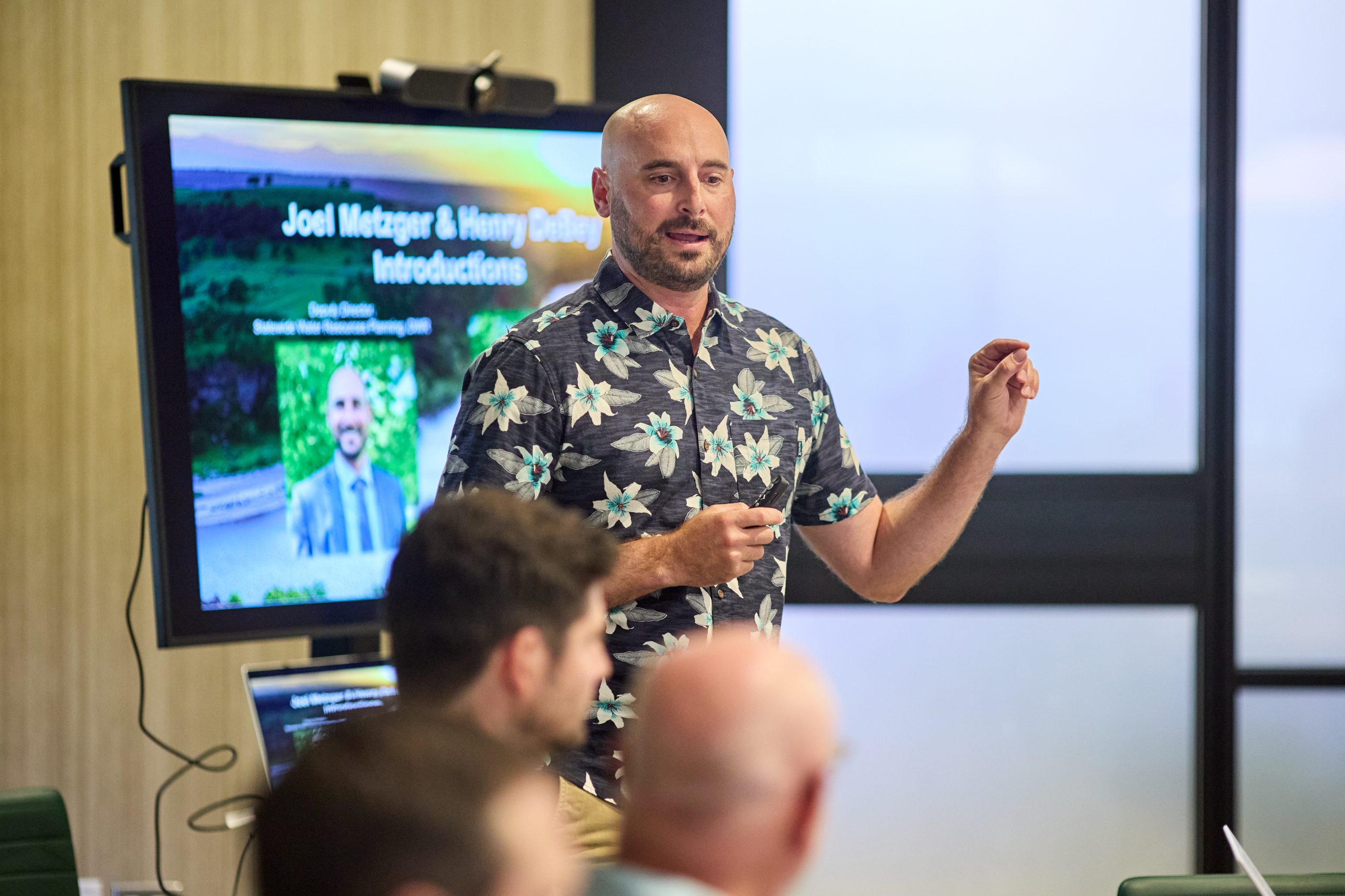 A man stands before a group of people in a meeting.